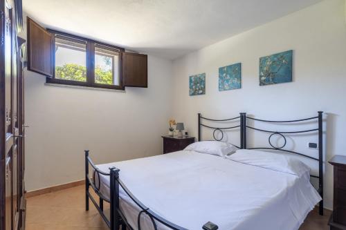 ein Schlafzimmer mit einem Bett mit weißer Bettwäsche und einem Fenster in der Unterkunft Casa Vacanze l'Olivastro in Àrbatax