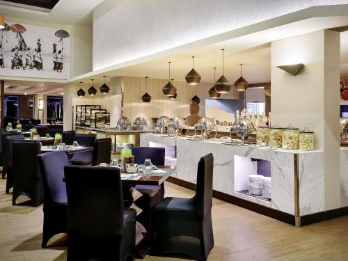 een restaurant met tafels en stoelen en een bar bij Pullman Bali Legian Beach in Legian