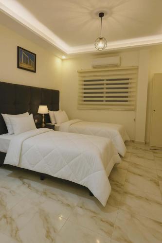 a bedroom with two white beds and a window at I cloud Petra hostel in Wadi Musa