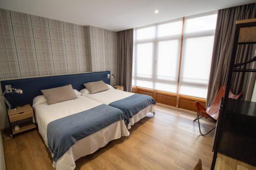 ein Schlafzimmer mit einem großen Bett und einem großen Fenster in der Unterkunft Hotel Montero in Mondoñedo