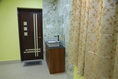 a bathroom with a wooden door and a shower curtain at Manab Palace in Kendrāparha