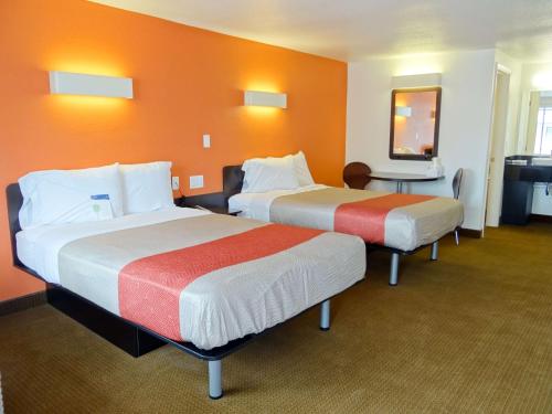 two beds in a hotel room with orange walls at Motel 6-Erie, PA in Erie