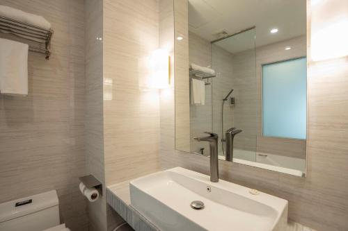 ein weißes Badezimmer mit Waschbecken und Spiegel in der Unterkunft Enrich Grand Hotel in Bangkok