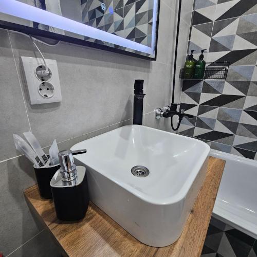 a white sink sitting on a wooden counter in a bathroom at Глинки 1комн in Semey