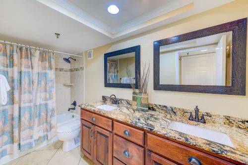 a bathroom with two sinks and a toilet and a mirror at Beachfront Balcony Sleeps 10 Heated Pool King Bed -308 in Debikot