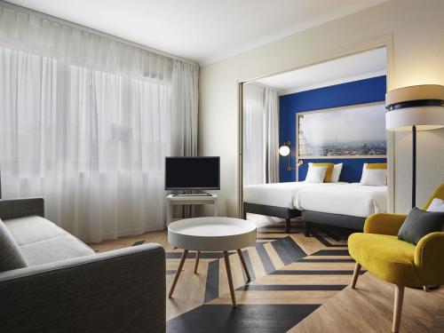 una camera d'albergo con due letti e un divano di Aparthotel Adagio Porte de Versailles a Issy-les-Moulineaux