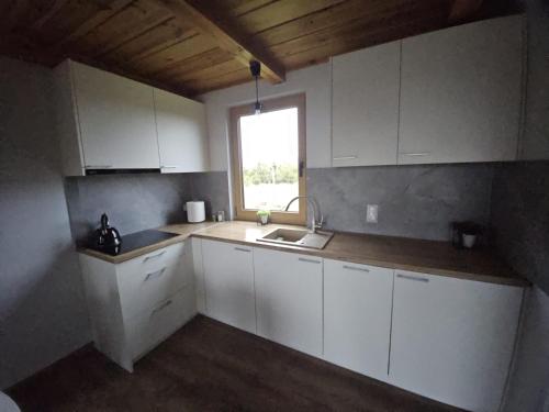 een keuken met witte kasten, een gootsteen en een raam bij PrzyStań pod Łysą Górą in Bostów
