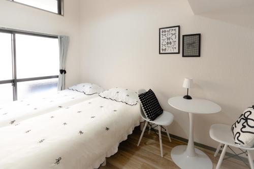 a bedroom with a bed and a table and chairs at Hani Stay Fukuoka Kaizuka-Timesカーシェアあり- in Fukuoka