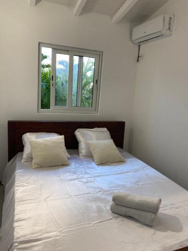 a bedroom with a large white bed with a window at Bungalow cerise in Morne-à-lʼEau