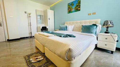 a bedroom with a large white bed with flip flops on it at Solkeb Hotel in Jijiga