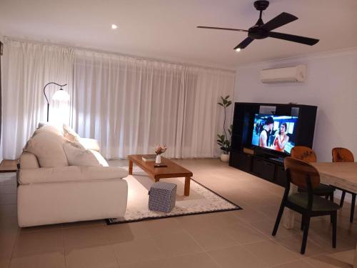 een woonkamer met een witte bank en een televisie bij Victoria Point Queen bed & Breakfast in Victoria Point