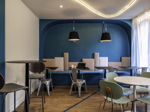 een restaurant met blauwe muren en tafels en stoelen bij ibis Styles Asnieres Centre in Asnières-sur-Seine