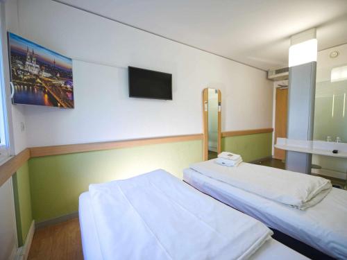 een ziekenhuiskamer met 2 bedden en een televisie bij Ibis budget Koeln Messe in Keulen