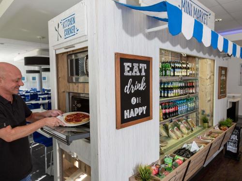 een man die een pizza haalt van een toonbank in een winkel bij Ibis budget Koeln Messe in Keulen