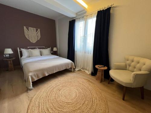 ein Schlafzimmer mit einem Bett, einem Stuhl und einem Fenster in der Unterkunft KE Urla in Urla