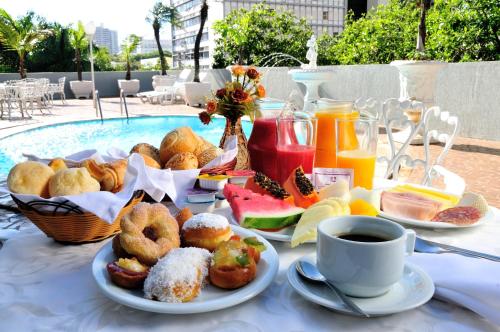 a table with breakfast foods and a cup of coffee at Jandaia Hotel Campo Grande in Campo Grande