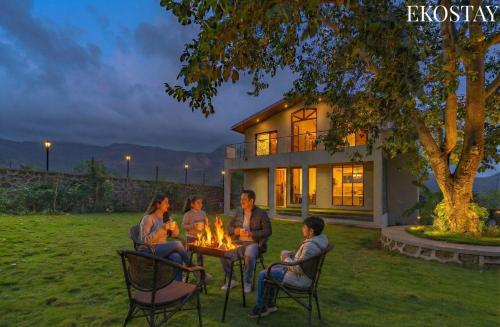 eine Gruppe von Menschen, die in einem Hof um ein Feuer sitzen in der Unterkunft EKOSTAY - Amani Villa in Khopoli