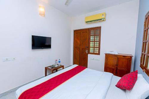 a bedroom with a bed and a tv on the wall at Greens Heritage Resort with Swimming Pool in Auroville