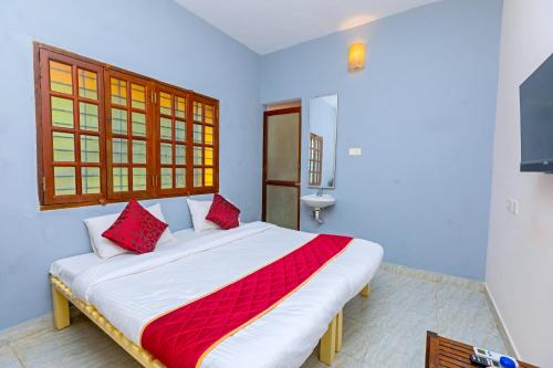 a bedroom with a large bed with red pillows at Greens Heritage Resort with Swimming Pool in Auroville