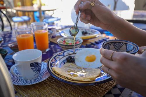 Een persoon die aan tafel eet, met een bord eieren erbij. bij Riad Salmiya Dune in Essaouira