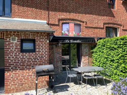 einen Tisch und Stühle vor einem Backsteingebäude in der Unterkunft Gîtes de la maison du haras in Beuvron-en-Auge