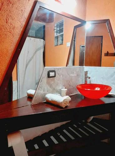 a bathroom with a red sink and a mirror at Tere & Tino Cabañas in Río Ceballos