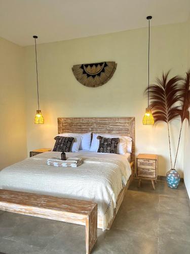 a bedroom with a large bed with a bench on it at Villa Santé ubud in Ubud