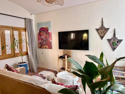 een woonkamer met een bank en een flatscreen-tv bij Riad Privatisé- Riad Dar Farida in Marrakesh