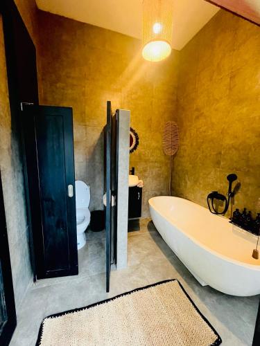 a bathroom with a large tub and a toilet at Villa Santé ubud in Ubud
