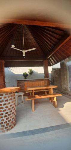 a picnic table and bench under a roof at Tebanyoman Guesthouse in Dalung
