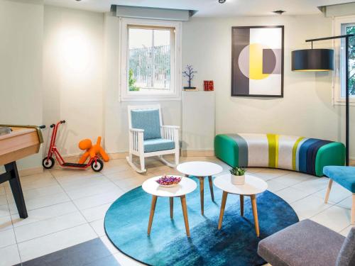 een woonkamer met een bank en tafels en een scooter bij Aparthotel Adagio Access Paris Porte De Charenton in Charenton-le-Pont