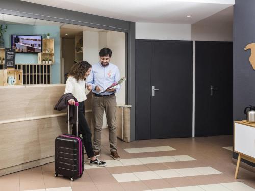 a man and a woman with luggage in an airport at Aparthotel Adagio Access Strasbourg Illkirch in Illkirch-Graffenstaden