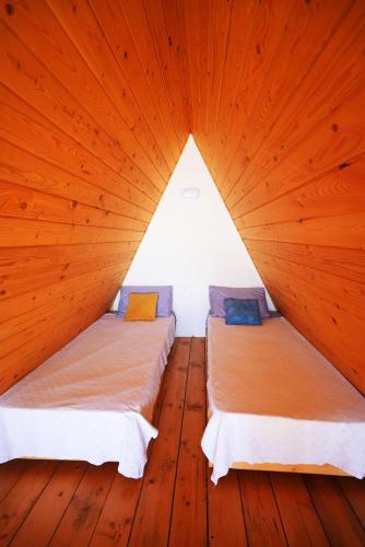 two beds in a room with wooden floors at La Madera Resort in Turbul