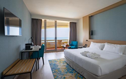 een hotelkamer met een bed, een bureau en een raam bij Occidental Sharjah Grand in Sharjah