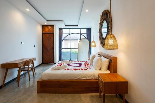 a bedroom with a bed and a desk and a mirror at Valentina House in Dalung