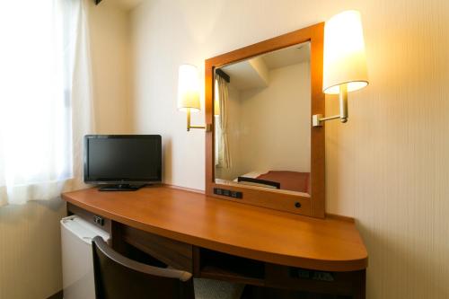 a room with a desk with a television and a mirror at Hotel New Ueno in Tokyo