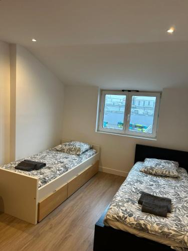 twee bedden in een kamer met twee ramen bij Le Naval - Confort Familial in Saint-Nazaire