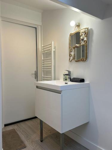 een witte badkamer met een wastafel en een spiegel bij Le Naval - Confort Familial in Saint-Nazaire