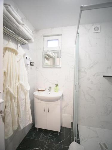 a white bathroom with a sink and a shower at Villa Magnat in Berehove
