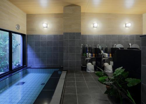 a bathroom with a swimming pool and a tub with toilets at Hotel Route-Inn Hita Ekimae in Hita