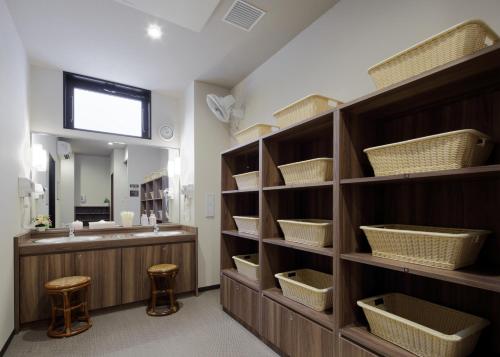 a bathroom with a sink and a large shelf with baskets at Hotel Route-Inn Hita Ekimae in Hita