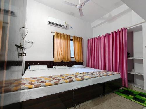 a large bed in a room with a pink curtain at NANDI Home's ujjain in Ujjain
