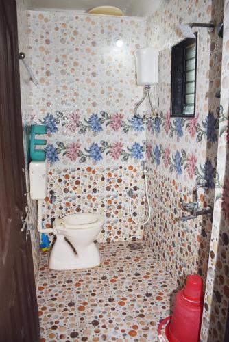 a bathroom with a toilet and flowers on the wall at Daneshwari Bhakt Niwas in Akalkot