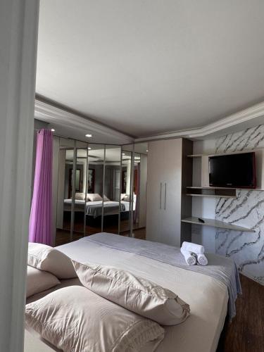 a bedroom with two beds and a flat screen tv at Refúgio da Lagoa in Florianópolis
