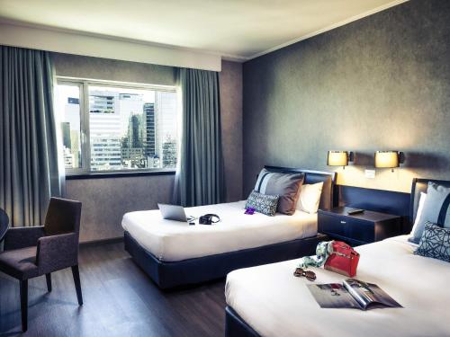 une chambre d'hôtel avec deux lits et une chaise dans l'établissement Mercure Santiago Centro, à Santiago