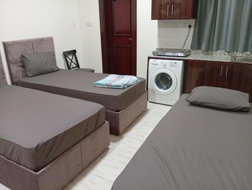 een kamer met 2 bedden en een wasmachine bij KhavaQatar Hostel 1 بيت مشترك in Doha