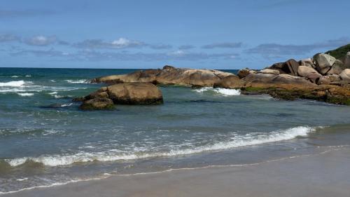 a group of rocks in the water on a beach at Cabana Rosa na mata in Imbituba