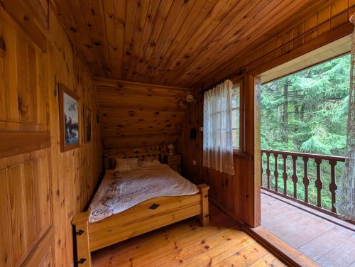 a bedroom in a log cabin with a bed and a window at Dowcień in Burdeniszki