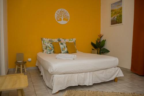 een slaapkamer met een bed met een oranje muur bij Kampagn Jacuzzi - Rémire Wifi et climatisation in Bourda