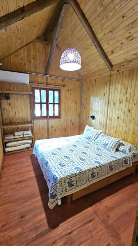 a bedroom with a bed in a wooden room at Cabaña Natural Del Bosque in Victoria